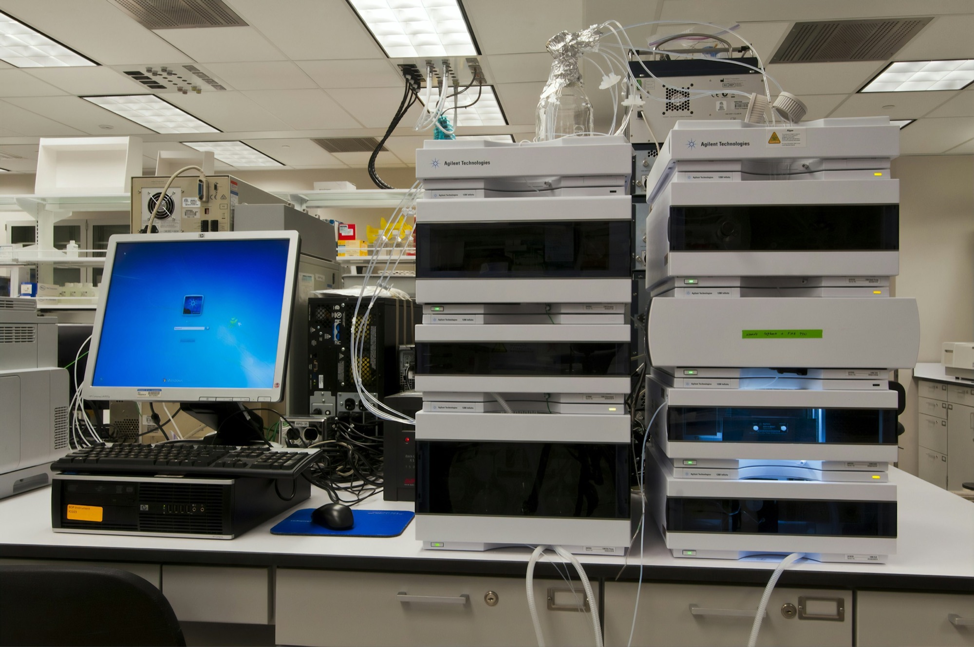 Liquid chromatography system stacked on a laboratory bench beside its control workstation